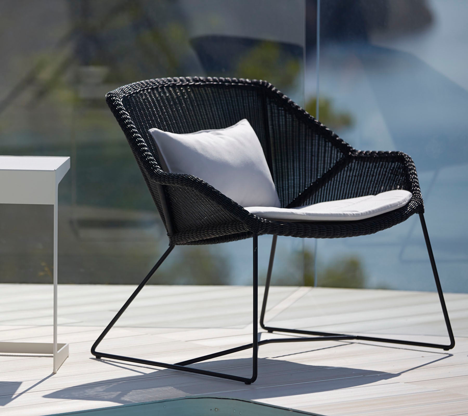 Chaise noire moderne avec coussin blanc dans un cadre de salon extérieur élégant.