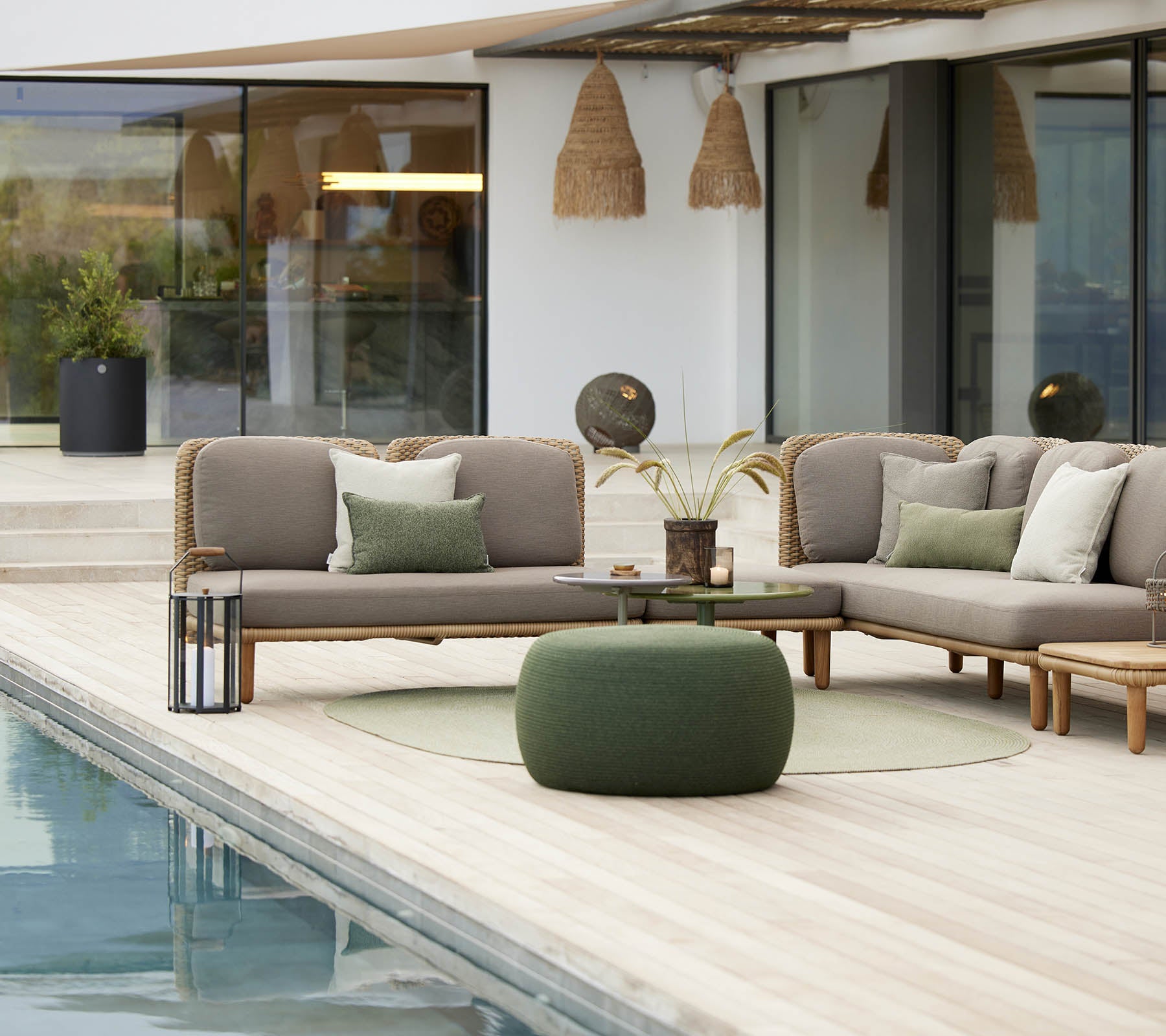 Espace de sièges élégant avec un pouf circulaire confortable et un design en arc, complété par des coussins décoratifs et de la verdure.