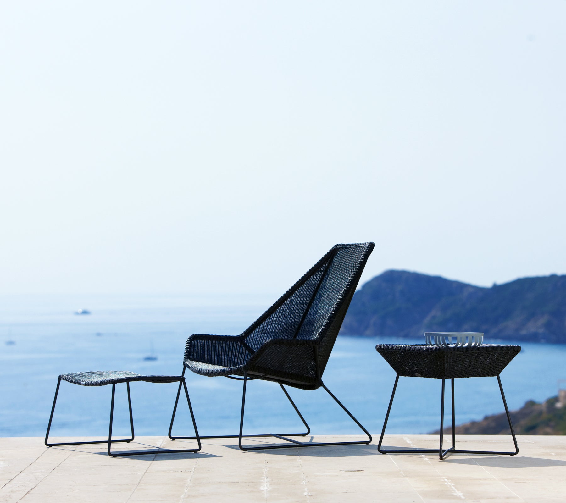 Chaise noire moderne et tables surplombant l'océan.
