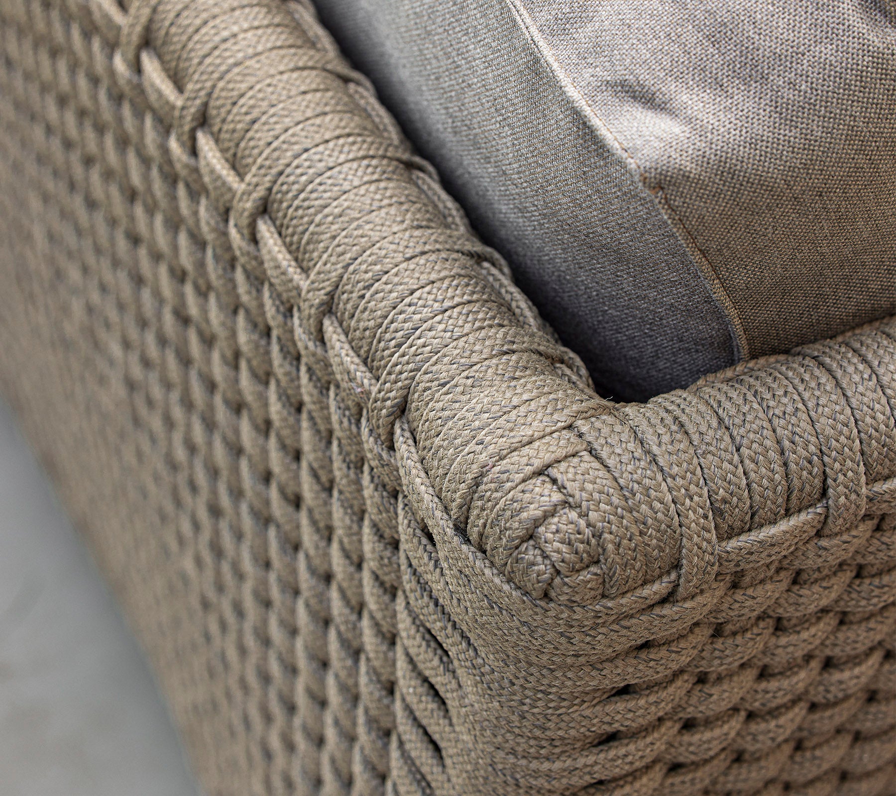Vue rapprochée d'un meuble en textile tissé, doté d'un coussin doux, mettant en évidence son design complexe et son schéma de couleurs neutres.