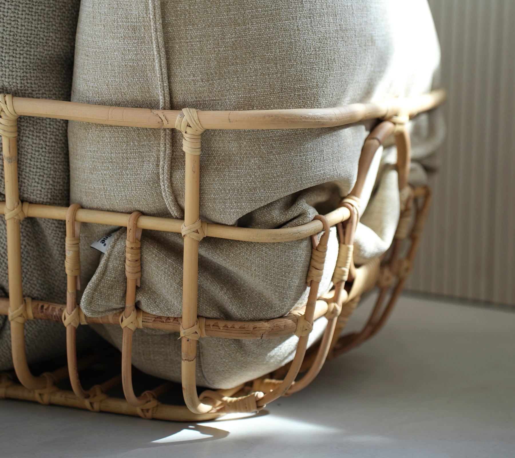 Coussin beige niché dans un panier tissé, montrant une esthétique bohème.