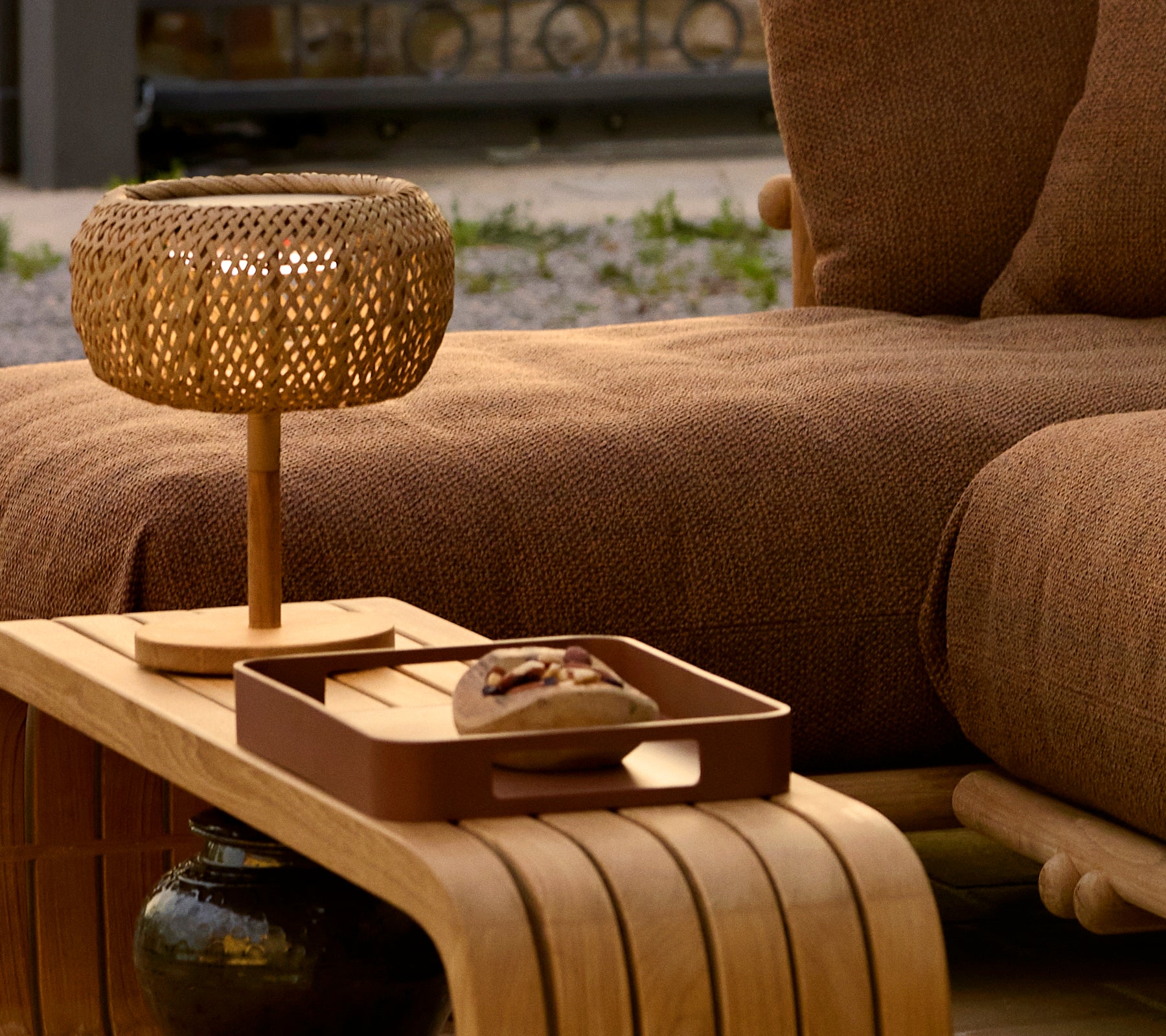 Une table basse en bois présentant un plateau décoratif et une lampe tissée, renforçant une atmosphère chaleureuse et élégante.