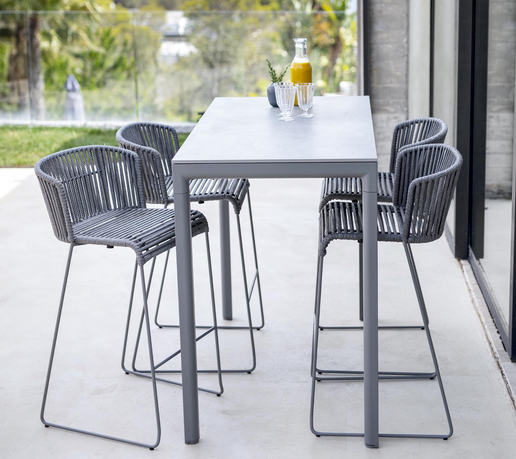 Ensemble de salle à manger moderne comprenant une table élégante et quatre chaises à dossier haut au design minimaliste, idéal pour des réunions décontractées.