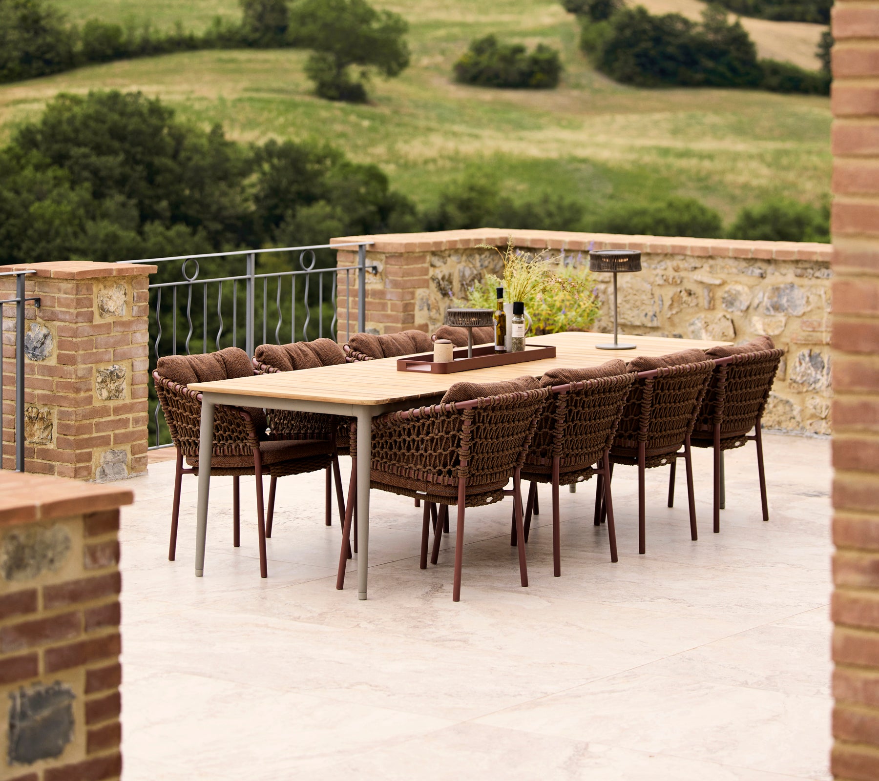 Chaises de salle à manger brun umber entourant une table à manger Core, sur fond d'un paysage verdoyant. Élégant agencement de salle à manger en extérieur.