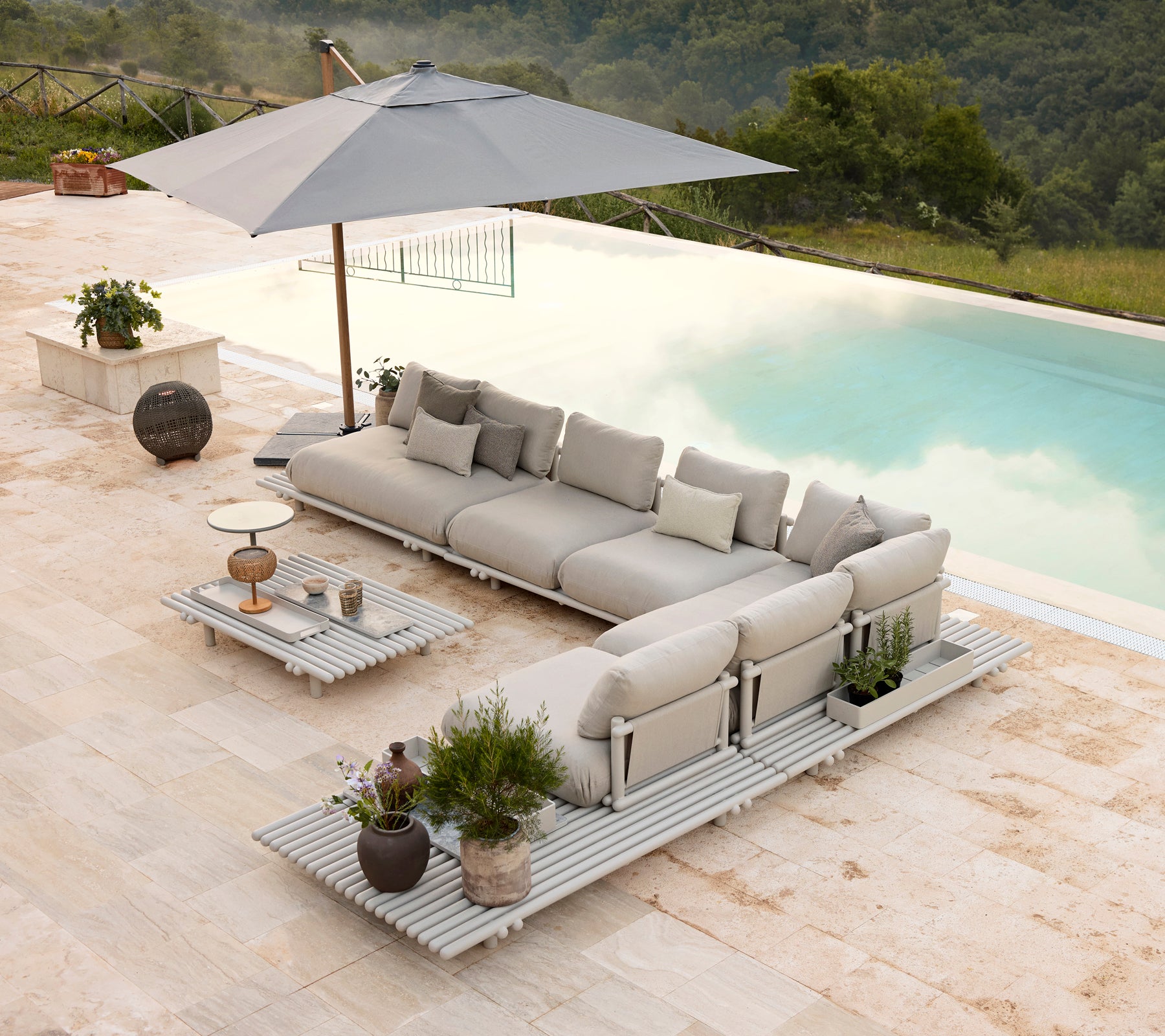 Ensemble de salon en aluminium élégant avec des coussins moelleux et une table basse assortie, complété par un parasol et des plantes décoratives.