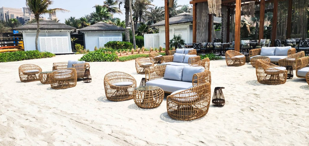 Beach lounge with sofas, round lounge chairs with grey cushions and round side tables