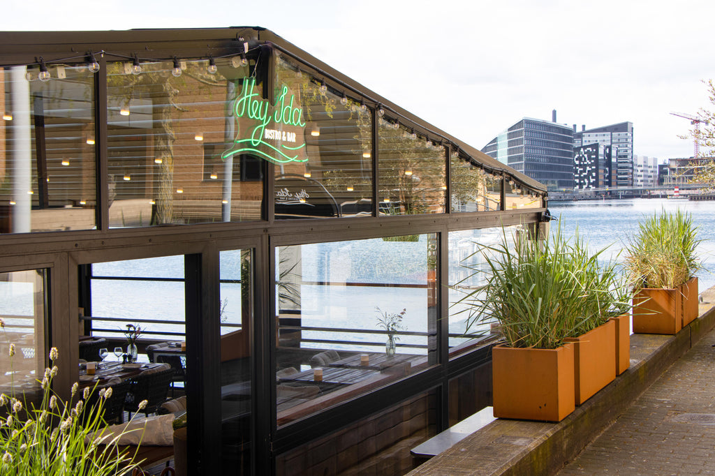 Green sign with Hey IDA, restaurant on water by Kalvebod Brygge in Copenhagen, lovely cobber planters with high grass