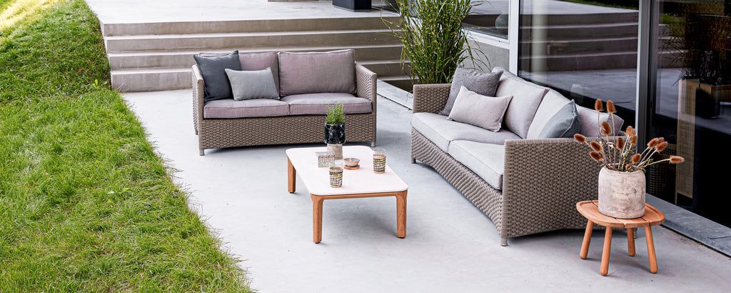 Stylish seating area featuring a sofa and chairs with pillows, a coffee table, and a decorative plant in a serene setting.