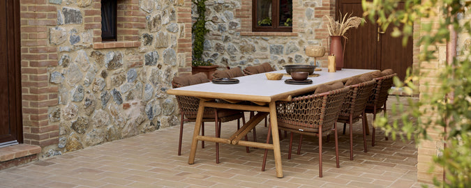 Une table à manger en bois avec des chaises en osier élégantes, ornée d'un bol décoratif et d'une configuration de table minimaliste.