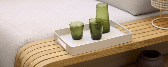 Un plateau de service élégant avec des verres verts disposés sur une surface en bois, complétant une esthétique minimaliste.