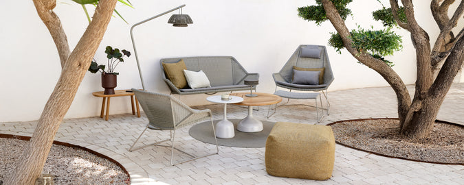 Configuration moderne de salon avec un canapé gris, une chaise grise, une table basse en bois et un pouf jaune.