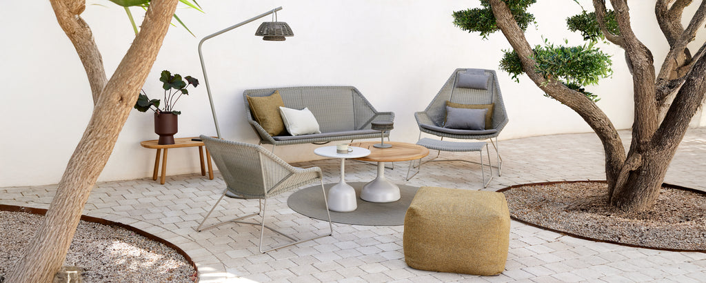 Configuration moderne de salon avec un canapé gris, une chaise grise, une table basse en bois et un pouf jaune.