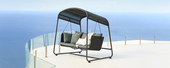 Balançoire moderne avec des coussins gris et un cadre noir surplombant une vue pittoresque.