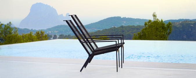 Chaise noire moderne positionnée près d'une piscine avec un arrière-plan pittoresque.