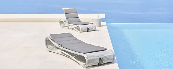 Des chaises longues modernes grises et blanches à côté d'une piscine.