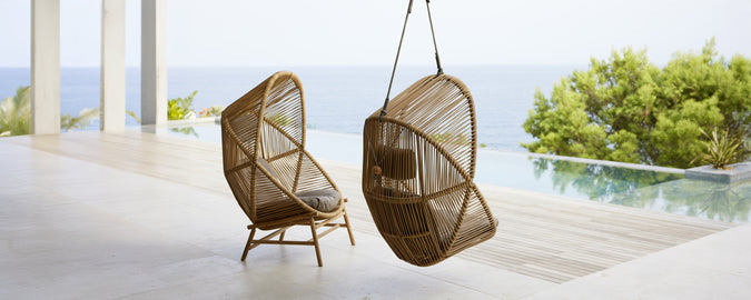Deux chaises suspendues modernes dans un cadre contemporain surplombant l'eau.