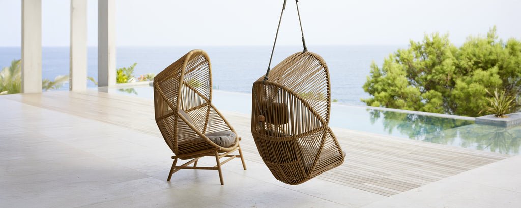 Deux chaises suspendues modernes dans un cadre contemporain surplombant l'eau.
