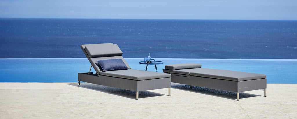 Chaise lounge grise et chaiselongue à côté d'une piscine avec vue sur l'océan.