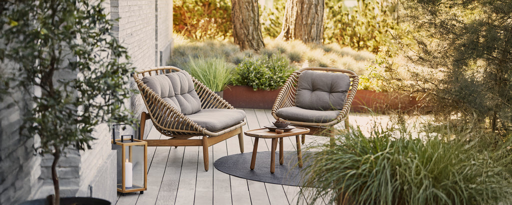 Chaises longues grises modernes avec des coussins et une petite table d'appoint dans un cadre extérieur.