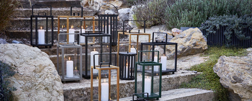 Des lanternes d'extérieur modernes en noir, or et vert disposées sur des marches en pierre.