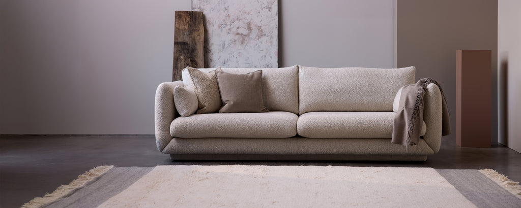 Canapé beige avec des coussins gris dans un cadre de salon moderne.