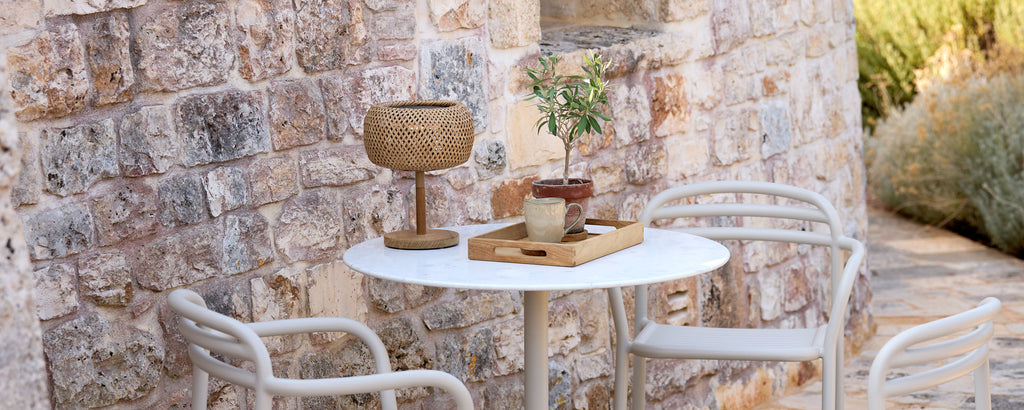 Cadre extérieur moderne avec une table blanche, des chaises blanches et des éléments décoratifs marron.