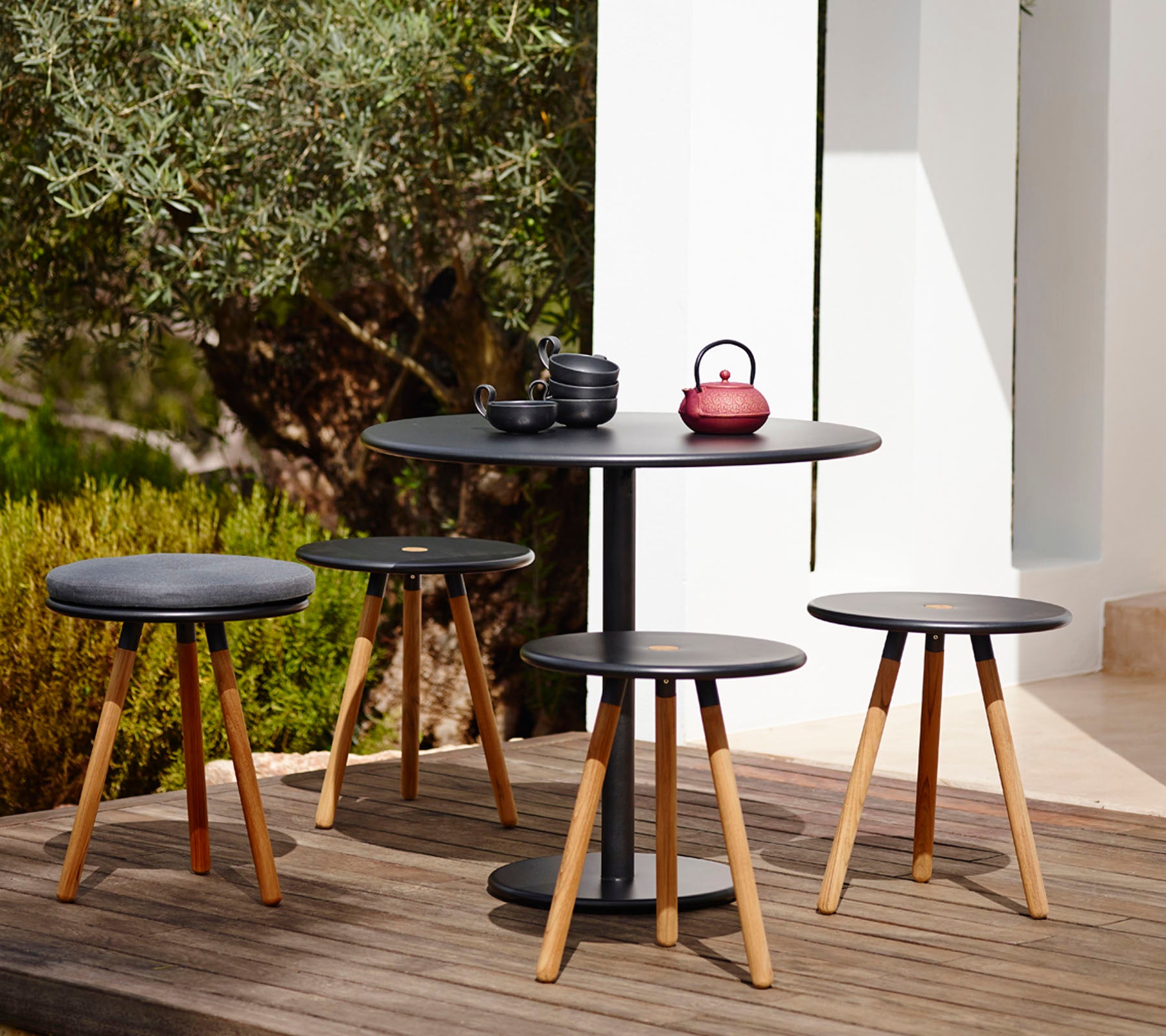 Ensemble de table et de tabourets noirs modernes dans un cadre de jardin extérieur.