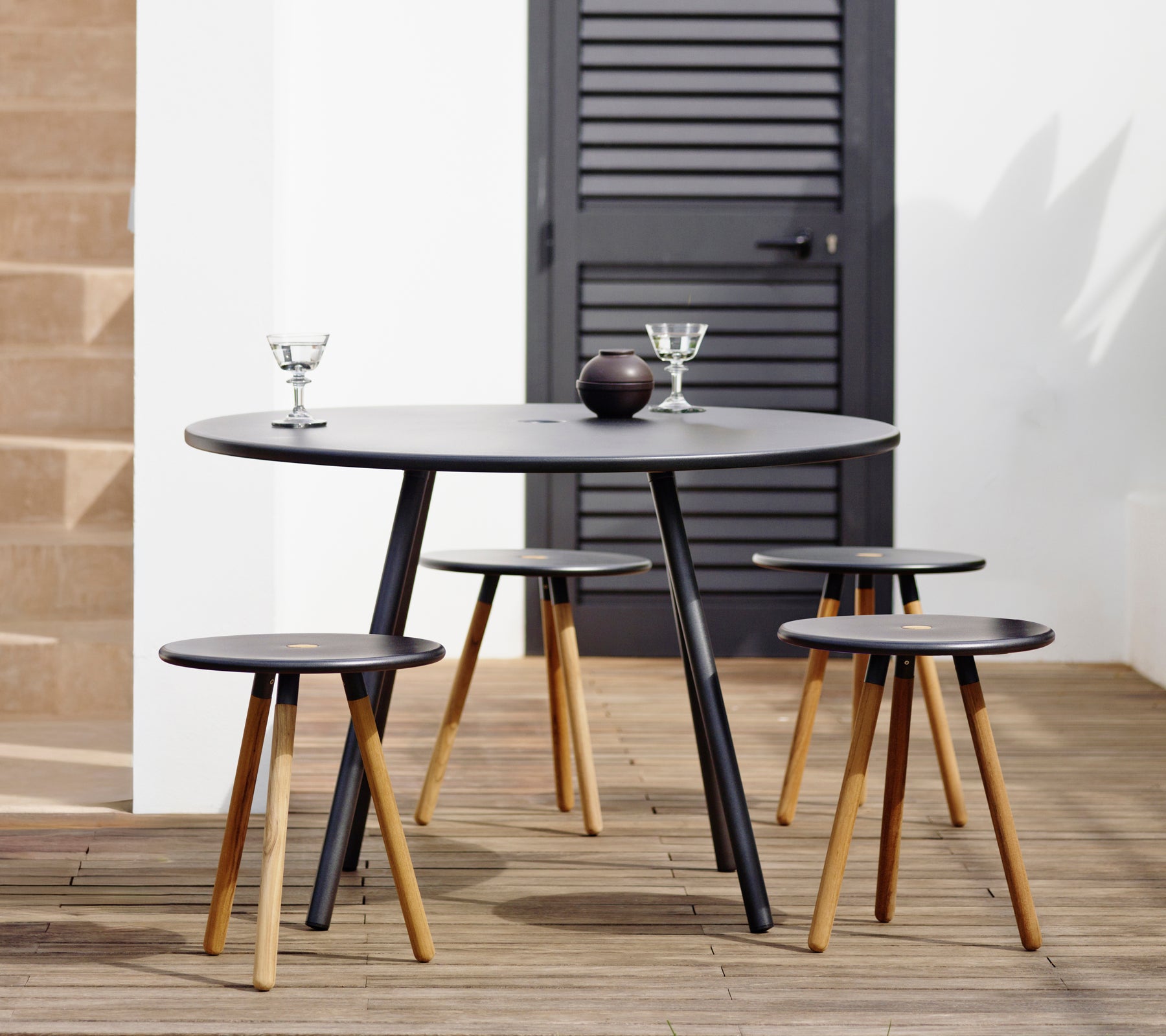 Table noire moderne avec tabourets assortis dans un cadre de salon élégant.