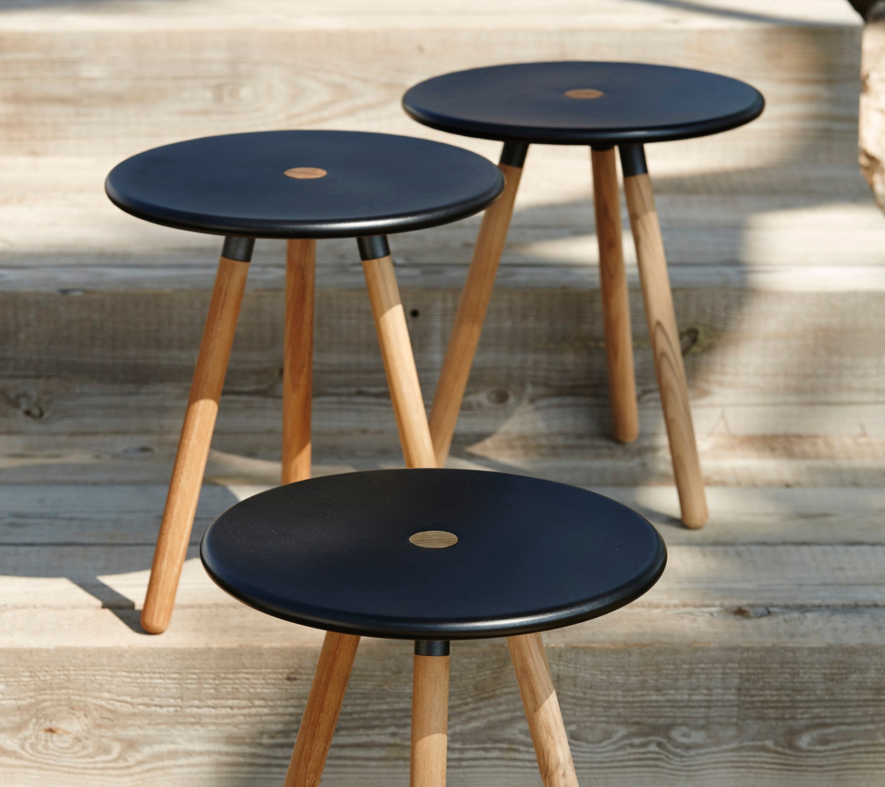 Trois tabourets noirs modernes avec des pieds en bois sur une surface en bois.