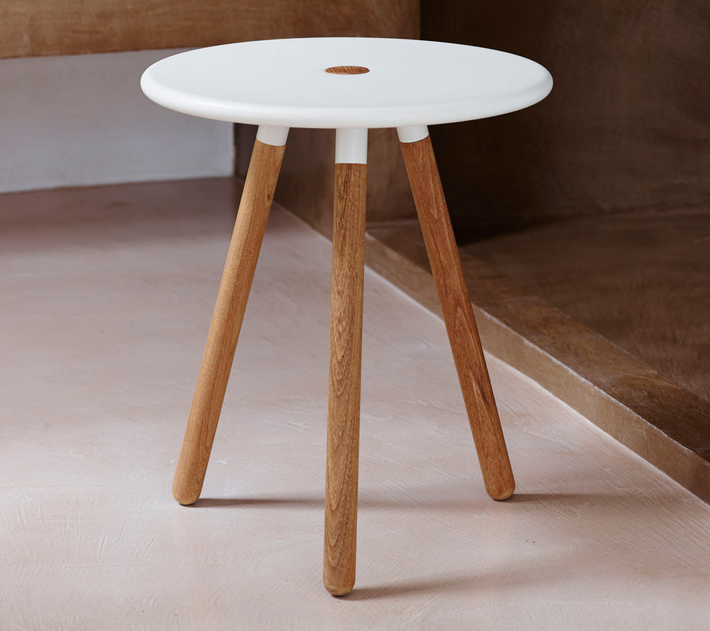 Une table ronde moderne avec un plateau blanc et des pieds en bois naturel, comportant un petit trou au centre pour un intérêt de design.