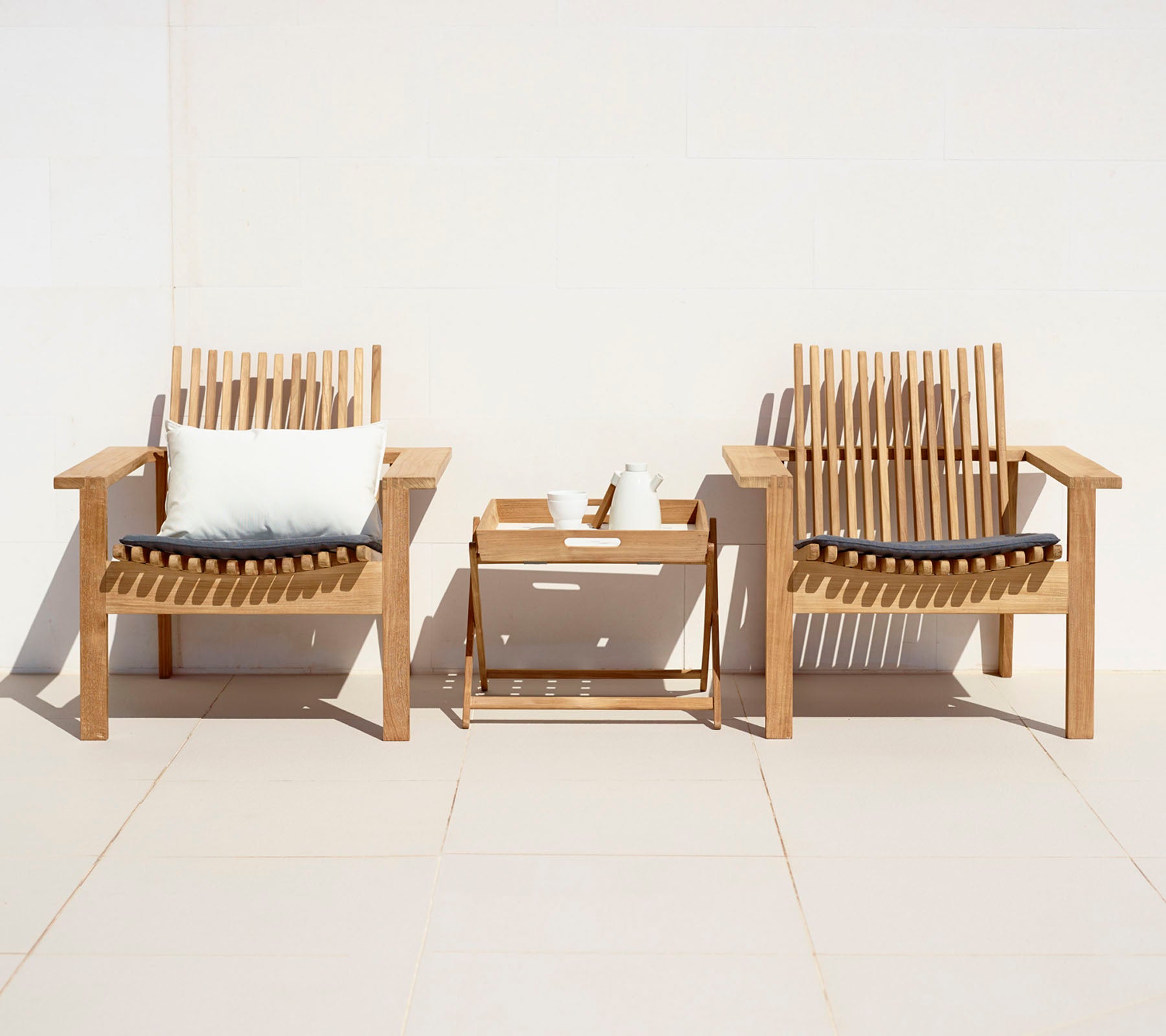Deux chaises en bois élégantes avec des coussins et une petite table d'appoint, créant un coin salon accueillant.