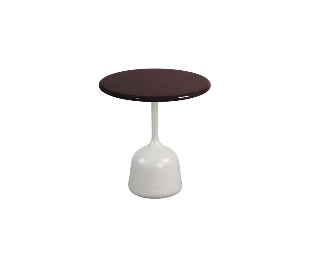 Table ronde bourgogne avec une base blanche dans un cadre de salon moderne.