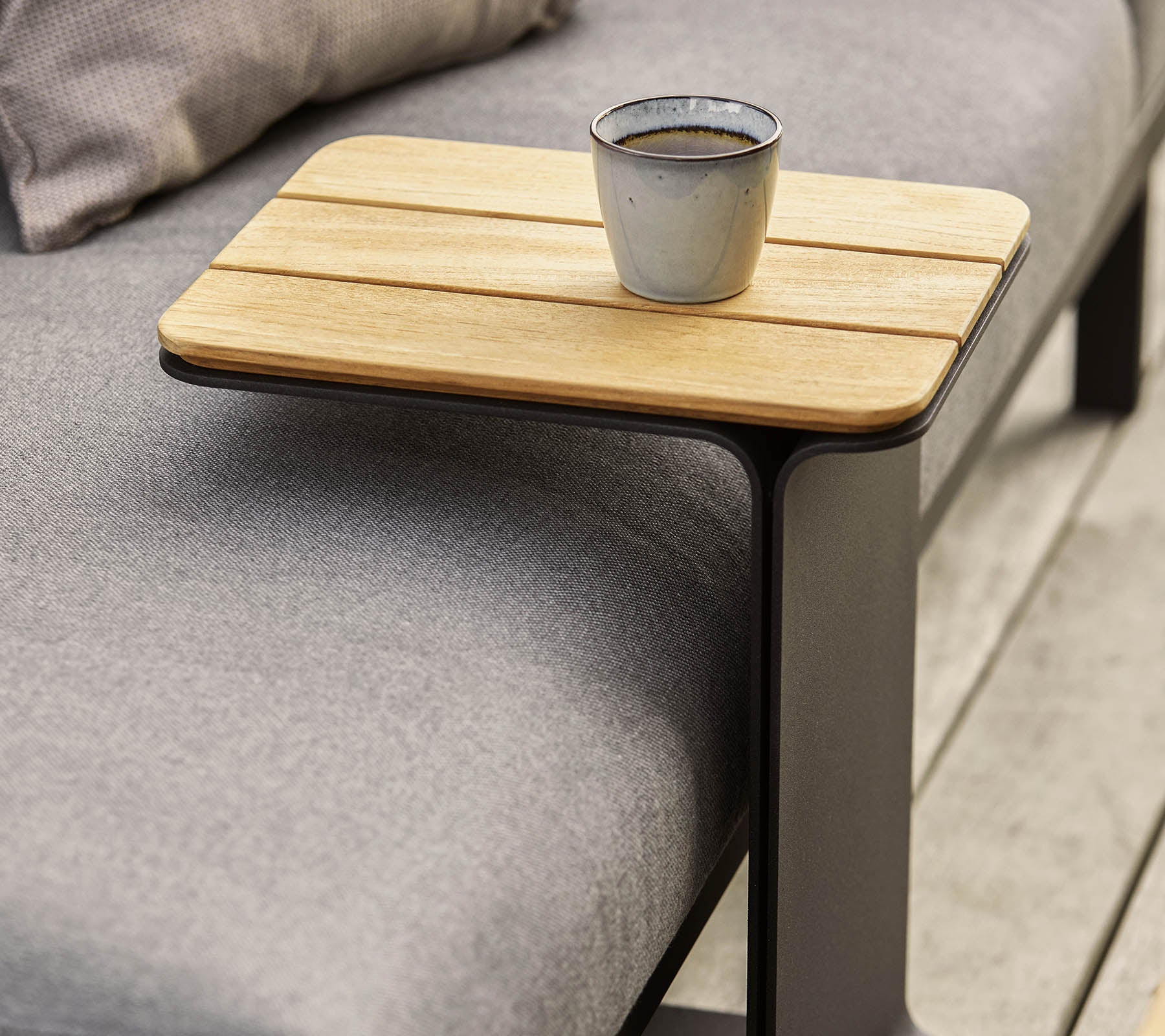 Une table d'appoint élégante avec un dessus en bois et un cadre métallique moderne, sur lequel est posée une petite tasse.