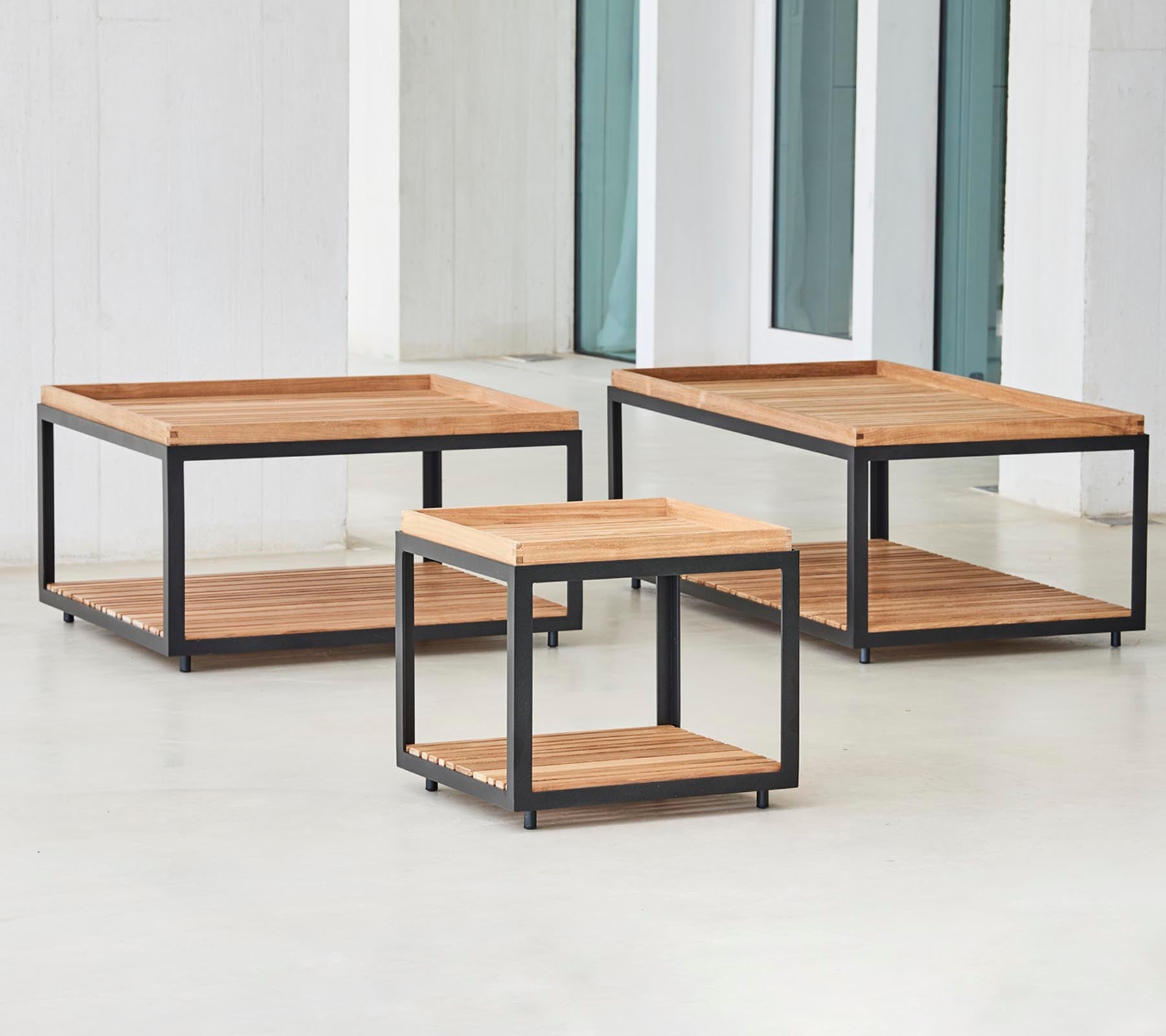 Trois tables basses en bois élégantes avec des cadres en métal noir de différentes tailles, équipées d'étagères ouvertes pour le rangement et l'affichage.