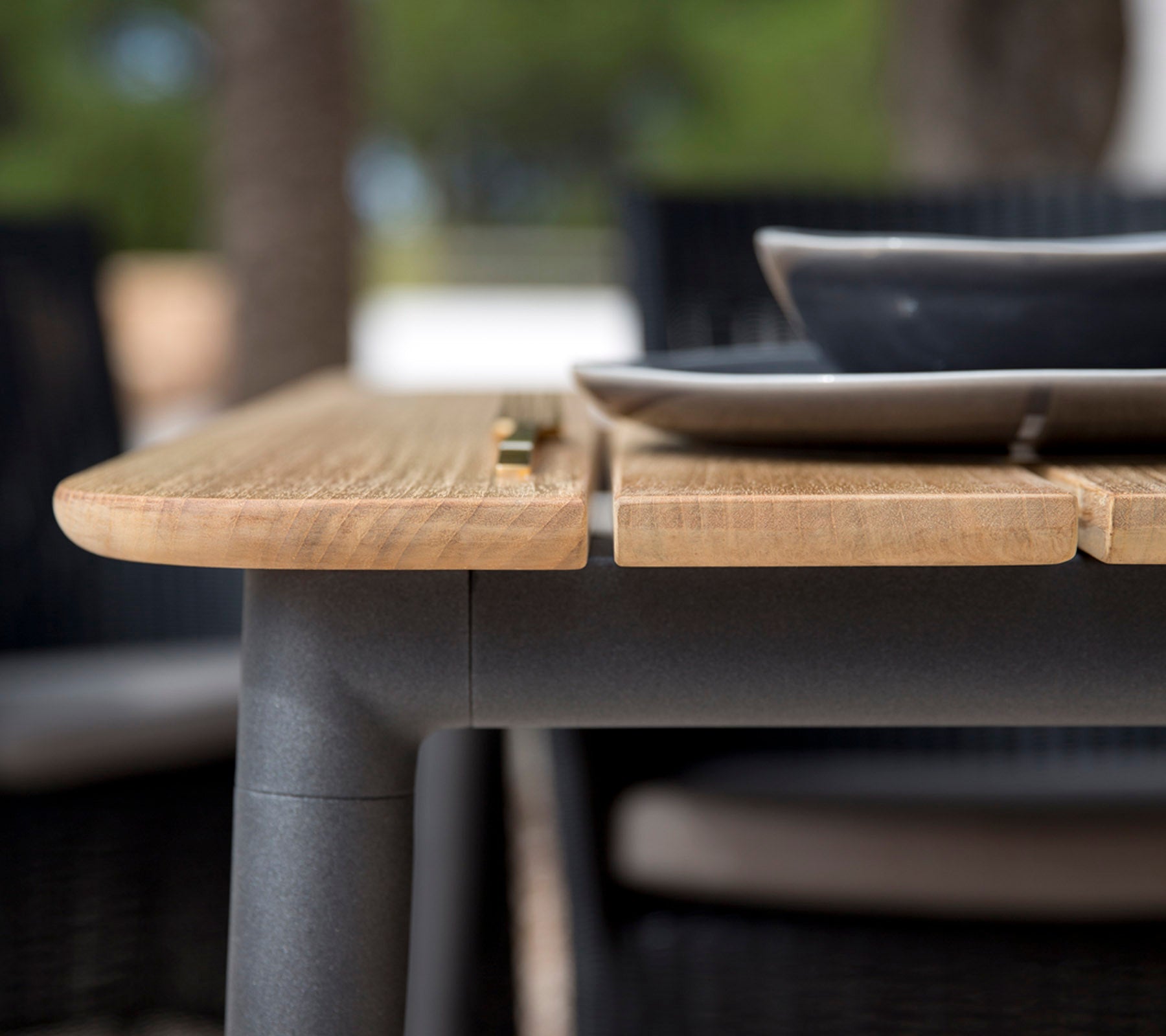 Gros plan d'un bord en bois avec une finition lisse, avec une assiette noire placée dessus, montrant un design moderne.