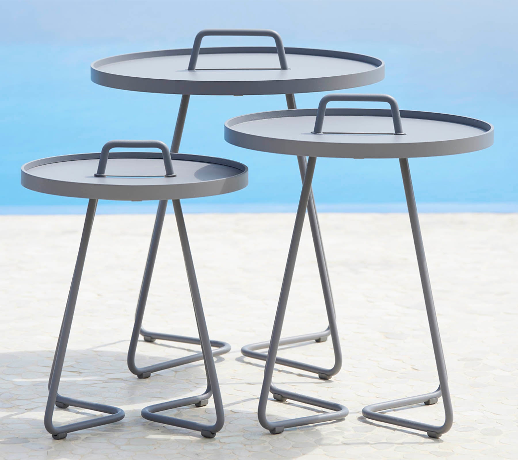 Trois tables rondes modernes avec des cadres en métal élégants et des surfaces planes, disposées en différentes tailles. Parfaites pour des options de style polyvalentes.
