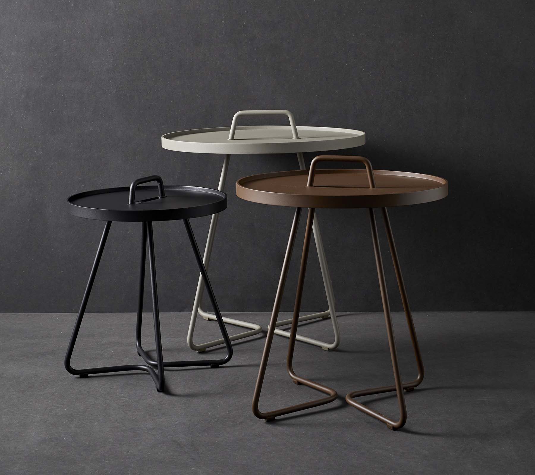 Trois tables d'appoint élégantes avec des tops ronds et des designs de poignées uniques, présentant un mélange de couleurs incluant le noir, le blanc et le brun.