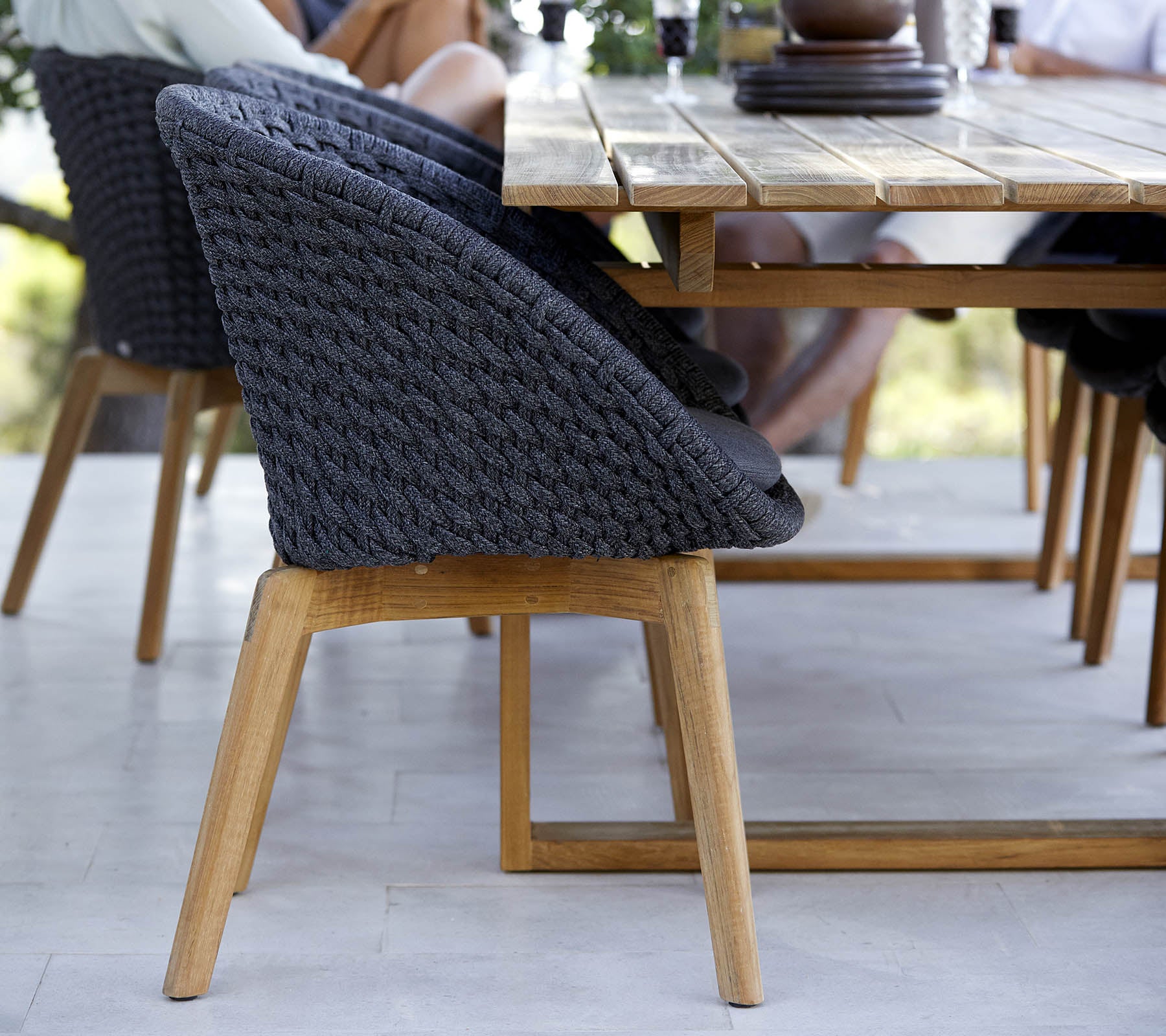 Chaise tissée élégante avec une base en bois, placée à côté d'une table, mettant en avant un design moderne parfait pour les espaces de rassemblement.