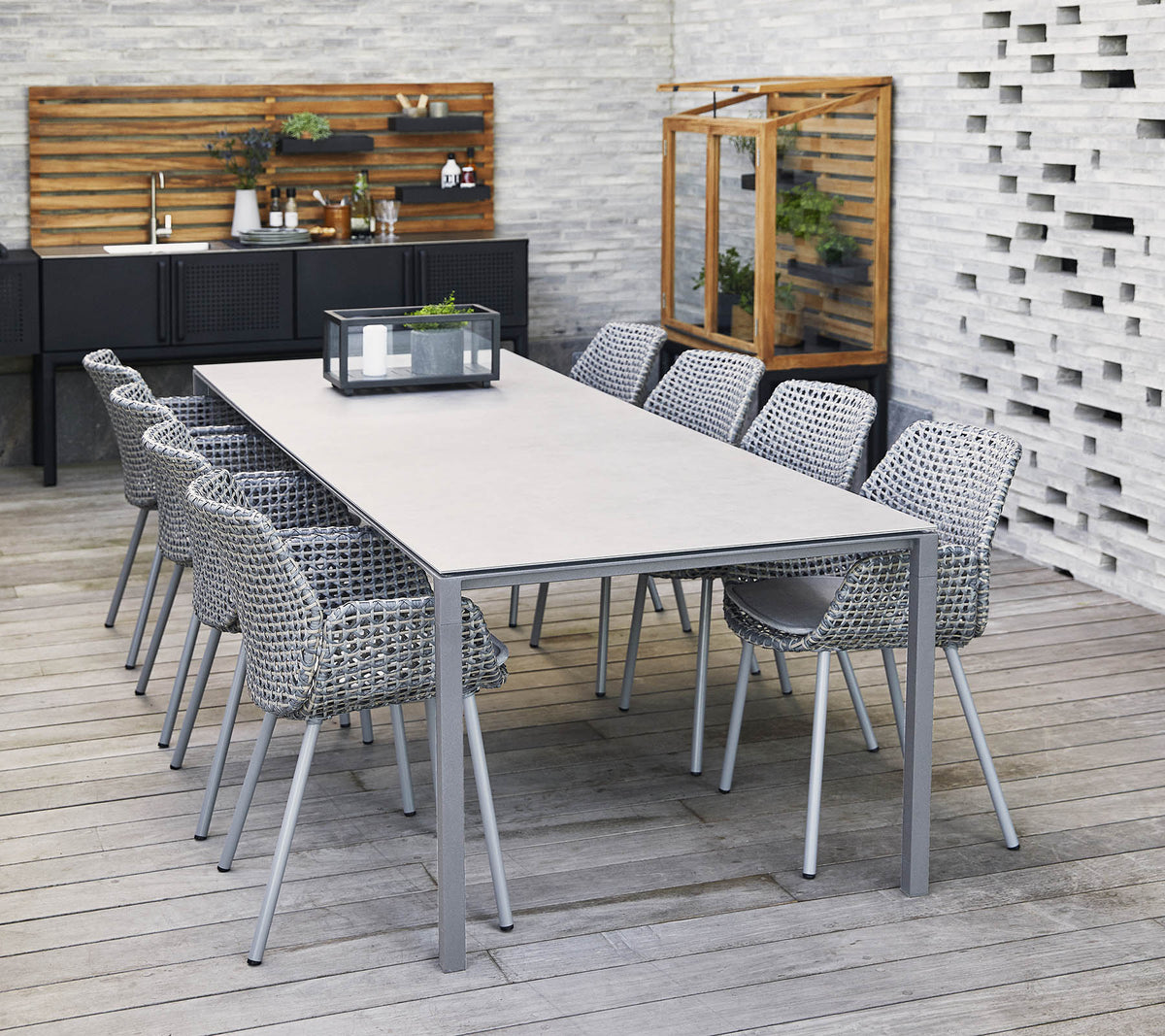 Une table longue et élégante entourée de chaises tressées, avec un centre de table et des éléments décoratifs dans un cadre contemporain.