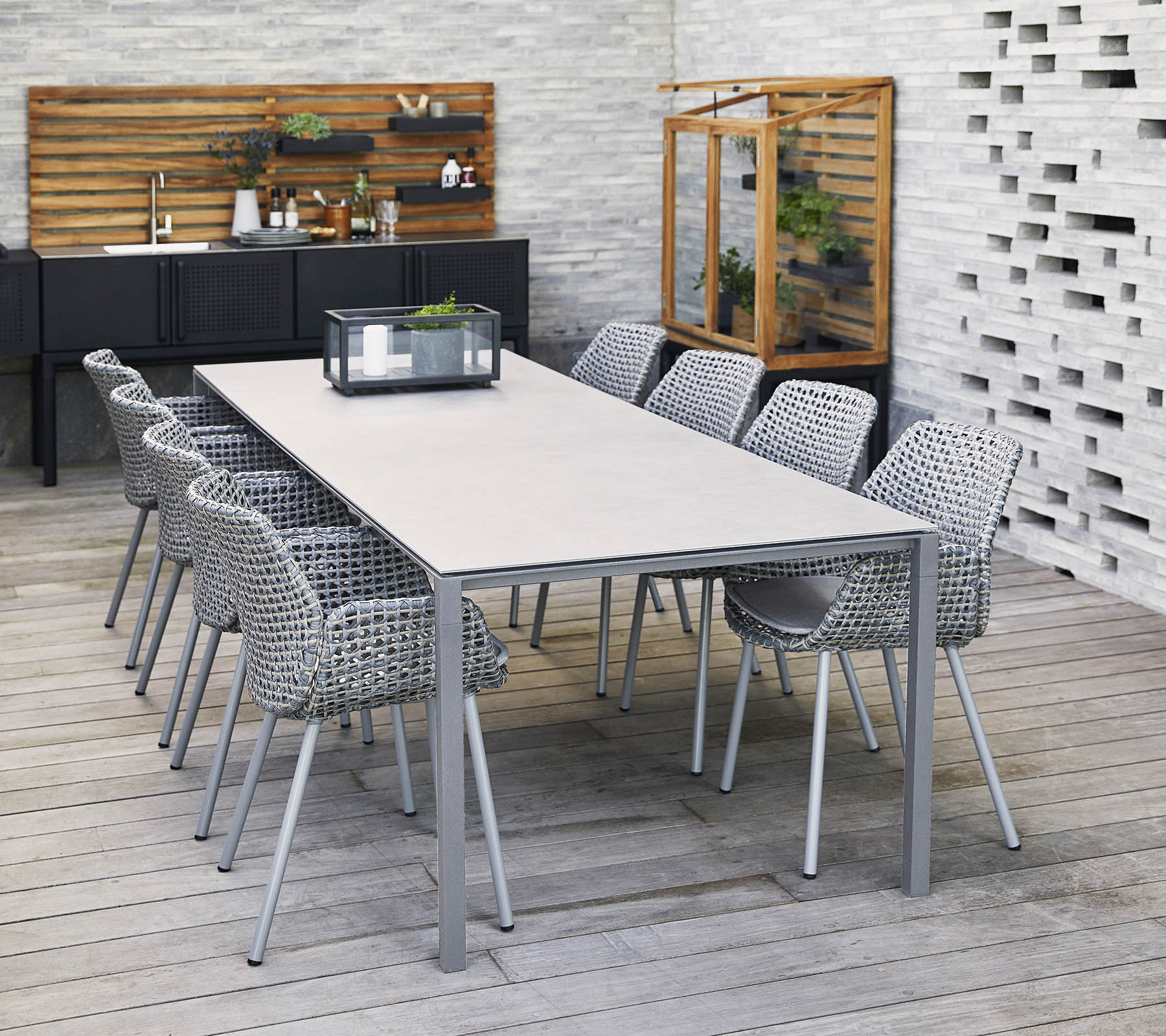 Une table longue et élégante entourée de chaises tressées, avec un centre de table et des éléments décoratifs dans un cadre contemporain.