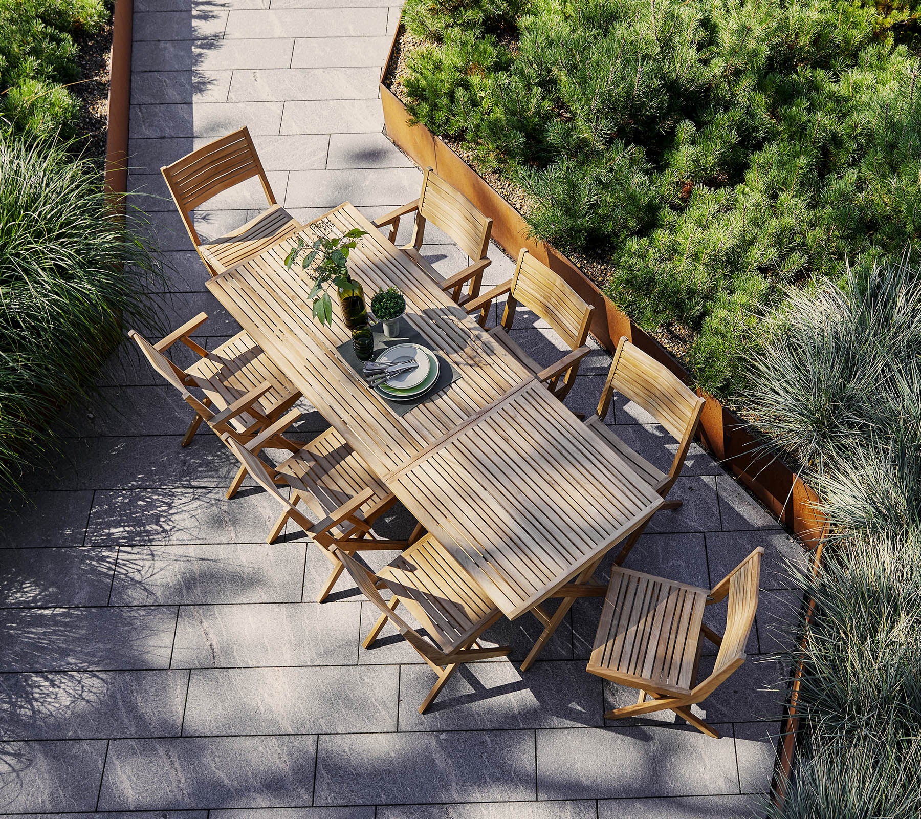 Une grande table à manger en bois entourée de chaises assorties, ornée d'une pièce centrale et encadrée par une verdure luxuriante.