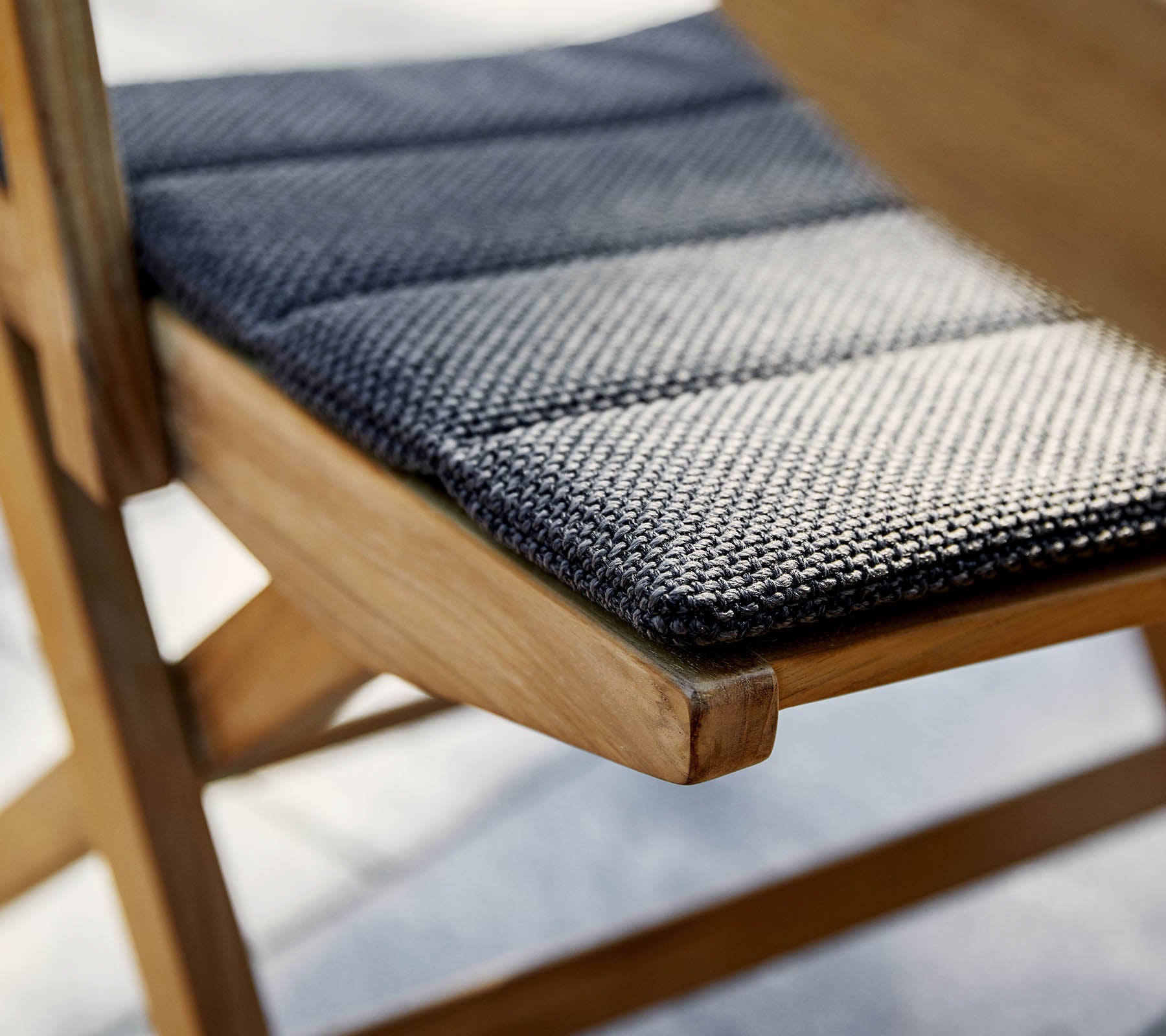 Gros plan d'un siège de chaise en tissu texturé noir et blanc sur un cadre en bois, mettant en valeur l'artisanat et les détails.