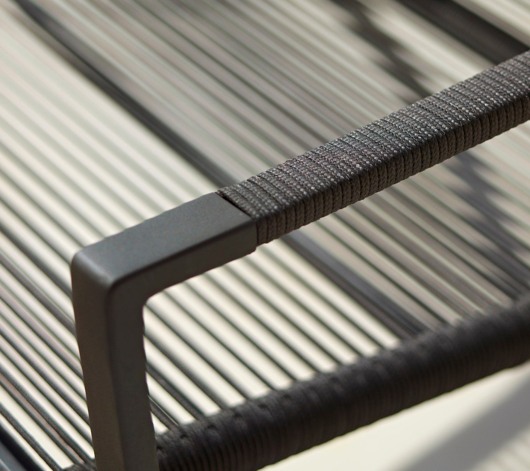 Gros plan d'un accoudoir de chaise moderne avec un design épuré, des détails texturés et une finition noire minimaliste.