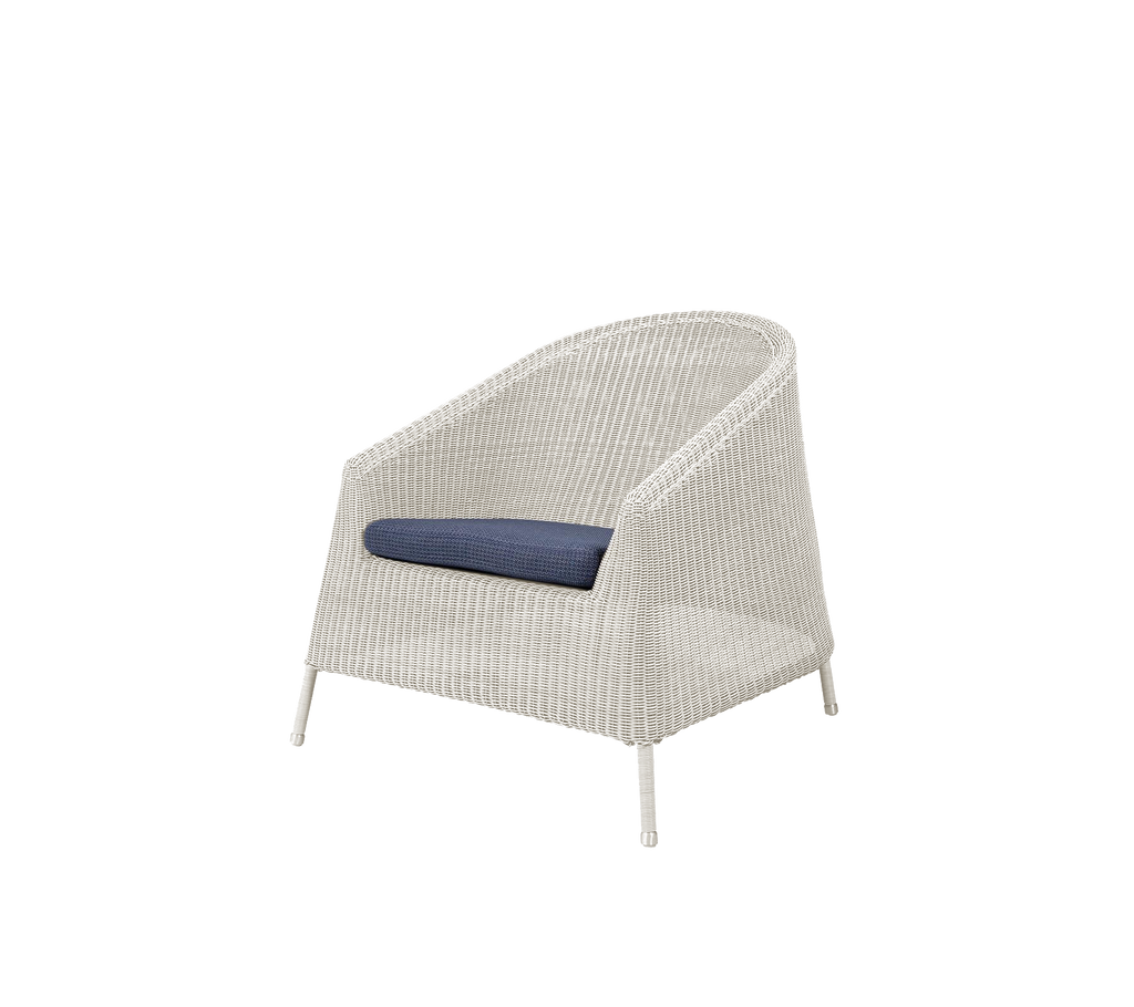 Chaise blanche moderne avec un coussin bleu dans un cadre de détente.
