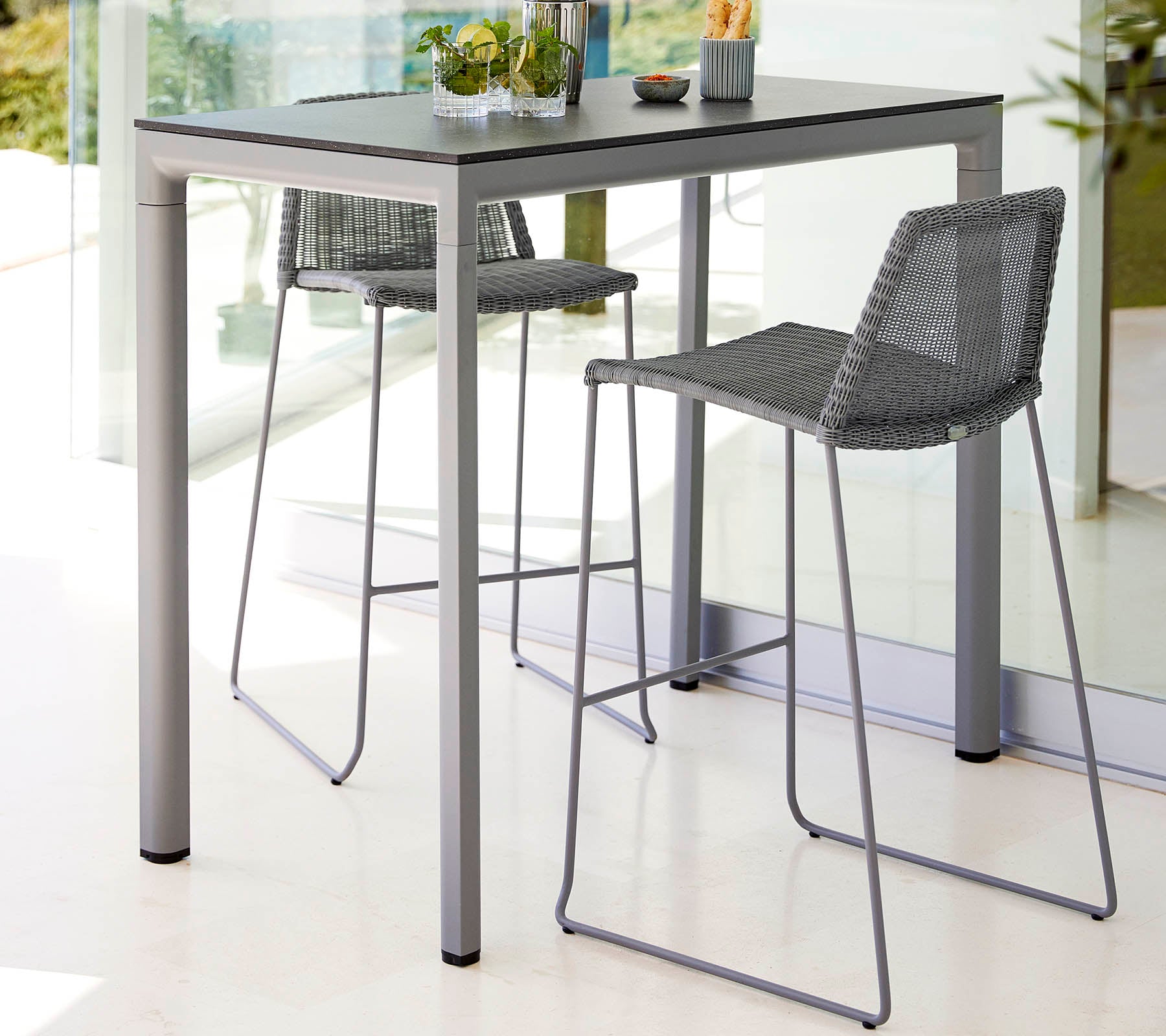 Une table élégante avec deux tabourets hauts, présentant un design moderne et une palette de couleurs claires, agrémentée d'un petit centre de plante.