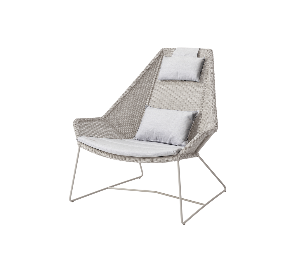 Chaise moderne gris clair avec coussins dans un cadre de salon.