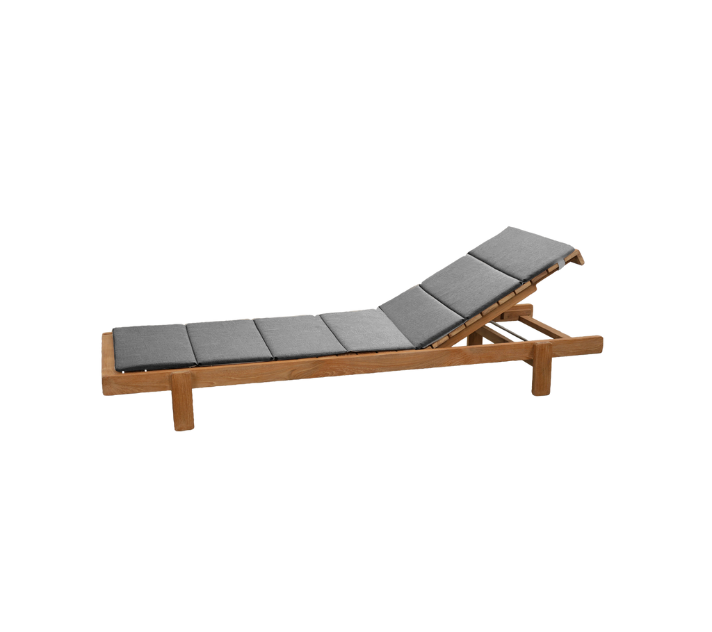 Chaise longue en teck avec coussin gris dans un cadre lounge.