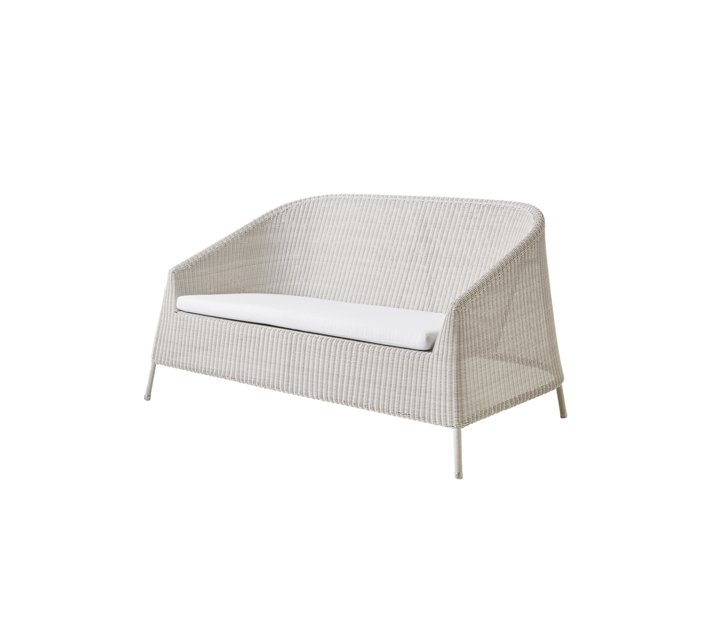 Canapé moderne couleur sable avec un coussin blanc dans un design minimaliste.