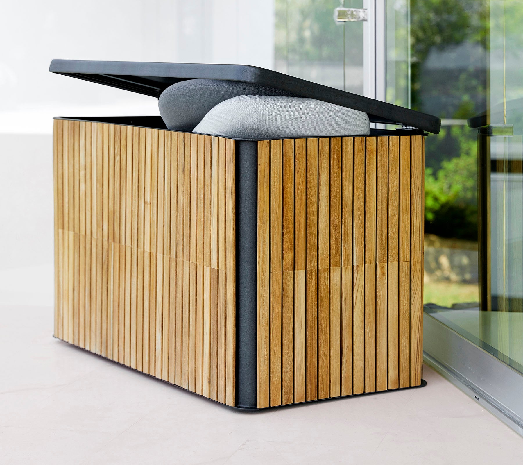 Boîte de rangement élégante avec un extérieur en bois à lamelles et un couvercle à charnière, doté d'un dessus rembourré pour plus de confort et de fonctionnalité.