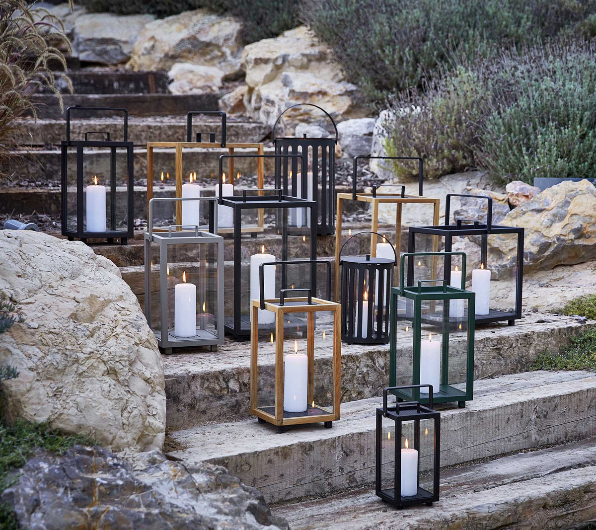Collection de lanternes décoratives dans divers styles et couleurs, avec une douce lumière de bougie, artistiquement disposées sur des marches en pierre.